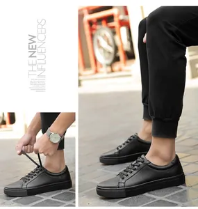 Detailed view of men's casual black leather low-top sneakers in an outdoor setting.