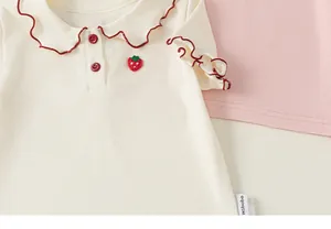 Close-up of baby girl's t-shirt with sweet doll collar and strawberry embroidery