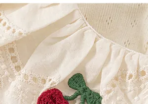 Close-up view of girl's summer t-shirt featuring a lace collar and cherry embroidery detail.
