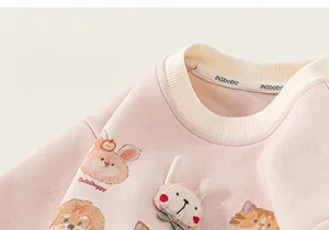 Primo piano di una felpa rosa da bambina con toppe di animali e scollo a costine