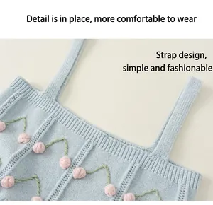 Close-up of blue knitted girl's top with 3D pink cherry embroidery and thick straps.