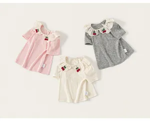 Detail of three girls' summer t-shirts featuring lace collars and cherry embroidery