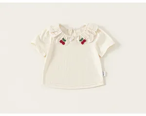 Detail view of girls' white T-shirt featuring ruffled lace collar and cherry embroidery