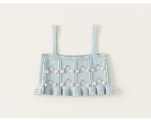Detailed macro view of soft light blue knit top for girls with pink cherry pom-poms