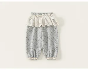 Dettaglio ravvicinato di pantaloni grigi a pois per neonata con eleganti ruches in pizzo