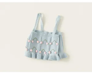 Detail view of light blue knitted baby girl top with 3D pink cherry embroidery
