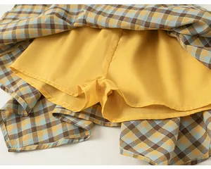 Dettaglio dei pantaloncini di sicurezza gialli integrati sotto una gonna scozzese da bambina