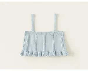 Close-up of a light blue knitted sleeveless top with ruffled hem and ribbed details.