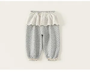 Vista dettagliata dei pantaloni grigi a pois per bambina con eleganti volant in pizzo.