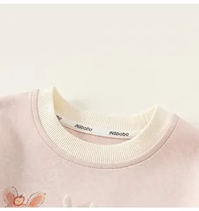 Vista dettagliata della scollatura rotonda a coste crema su una felpa rosa da bambina