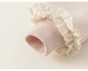 Primo piano del polsino di una felpa rosa per bambina con bordo in pizzo color crema.