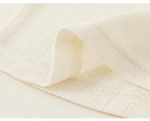 Close-up detail of delicate pointelle knit texture and fine stitching on a girl's T-shirt