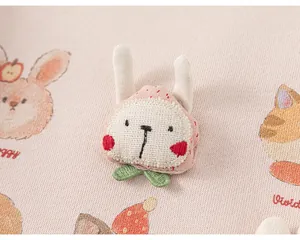 Primo piano di felpa rosa per bambina con stampe di animali e toppa a forma di coniglietto.