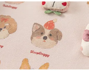 Vista dettagliata di stampe di cani e ricami su una felpa rosa da bambina piccola