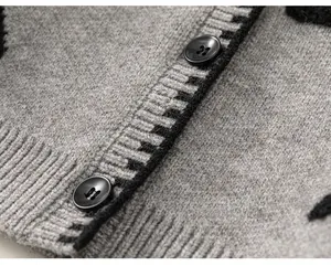 Detailopname van een grijs gebreid vest met zwarte knopen en sterpatroon