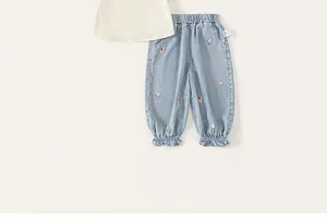 Detailed view of toddler girl's denim pants with floral embroidery and ruffled hems