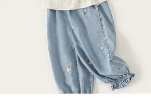 Close-up of baby girl light blue denim pants featuring colorful floral embroidery