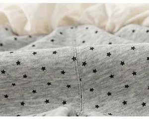 Dettaglio macro del morbido tessuto a maglia grigio con motivo a stelle nere per felpa da bambina