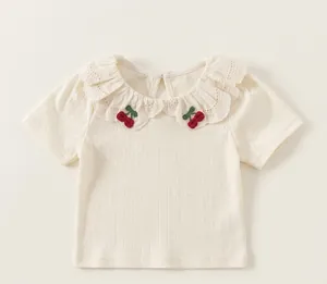 Detailed view of girls' white T-shirt featuring a lace ruffle collar and cherry embroidery.