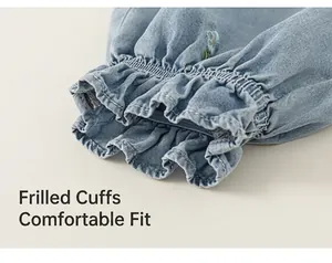 Macro view of elastic ruffled cuff on blue denim pants with delicate floral embroidery