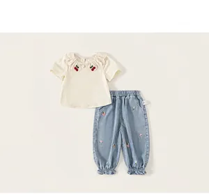 Detail view of toddler girl summer outfit with cherry embroidery and floral denim pants