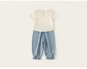 Detailed view of a baby girl's outfit featuring a scalloped lace collar and ruffled pants.