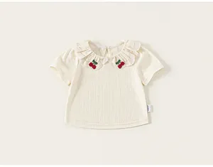 Detailed view of baby girl cream t-shirt with ruffled collar and cherry embroidery.