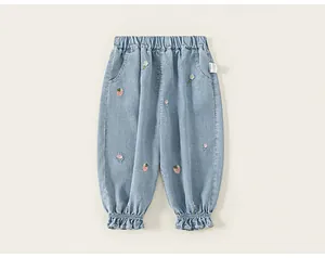 Detailed shot of light blue denim pants for girls with strawberry floral embroidery.