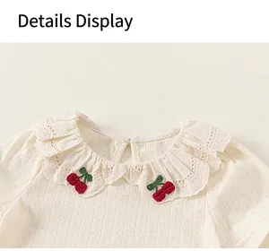 Close-up of baby girl's top featuring a ruffled lace collar with cherry embroidery