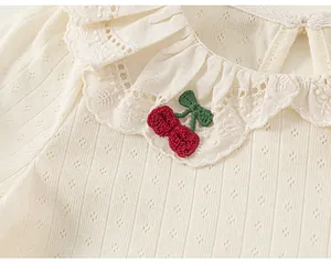 Close-up of baby girl T-shirt lace collar with red cherry embroidery detail