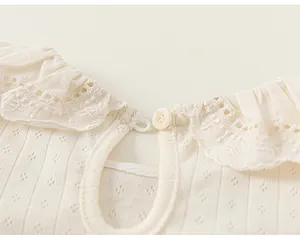 Close-up detail showing the intricate lace collar and back button on a baby girl's cotton T-shirt