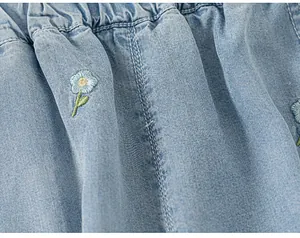 Close-up of delicate flower embroidery on soft light blue denim fabric for kids