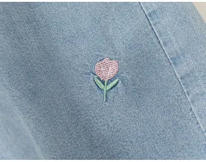 Close-up of pink flower embroidery on light blue denim fabric for girls' t-shirt