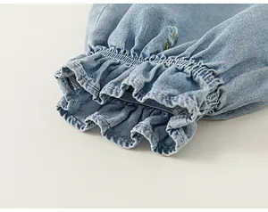 Detailed close-up of a child's denim sleeve cuff with ruffles and flower embroidery