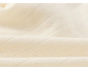 Close-up macro view of soft cream knitted pointelle fabric for baby girls t-shirts.