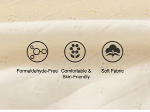 Close-up of soft cream-colored cotton fabric with delicate floral eyelet patterns