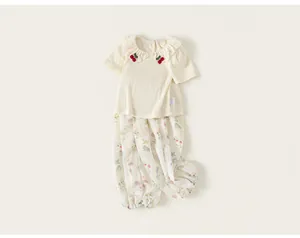 Close-up detail of a baby girl cream floral summer outfit with cherry collar embroidery