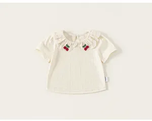 Detailed view of cream baby girl t-shirt with ruffle collar and cherry appliques