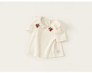 Detailed view of white toddler girl t-shirt featuring ruffle collar and cherry embroidery