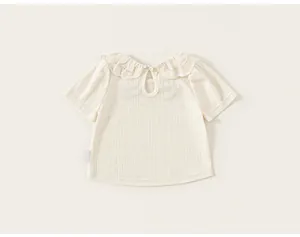 Close-up of baby girl's cream T-shirt with delicate lace collar and eyelet texture