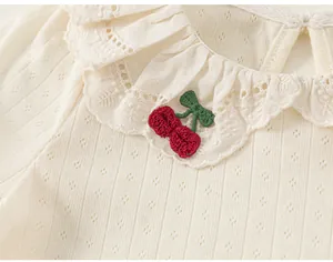 Close-up of baby girl's white t-shirt with ruffle lace collar and cherry embroidery