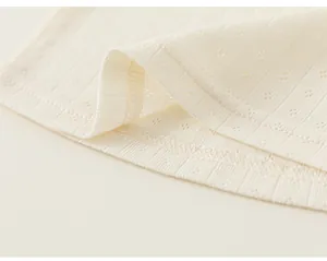 Close-up of cream pointelle knit fabric and stitching on a baby girl's T-shirt.