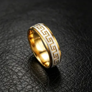 Close-up detail of titanium steel ring with gold Greek meander pattern on black leather.