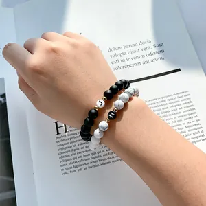 Detailopname van zwarte matte en witte marmeren kralenarmbanden met initialen J en N