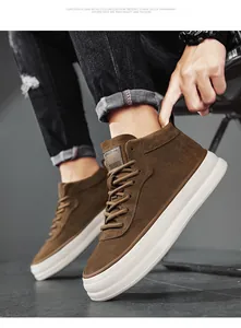 Close-up detail of brown suede mid-top sneakers featuring thick white soles and laces