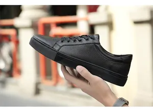 Handheld side view of black perforated cowhide low-top casual sneakers for men