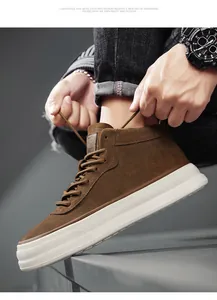 Macro view of brown suede mid-top thick-sole sneakers being laced up by model
