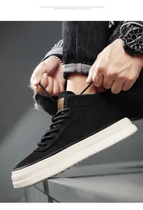 Close-up of black suede mid-top sneakers with thick white soles and lace-up detail