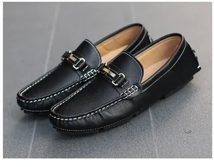 Detailed macro view of black leather men's loafers with metallic buckle decoration.