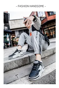 Detail shot of men's black and white mid-top skate shoes in an urban street setting.